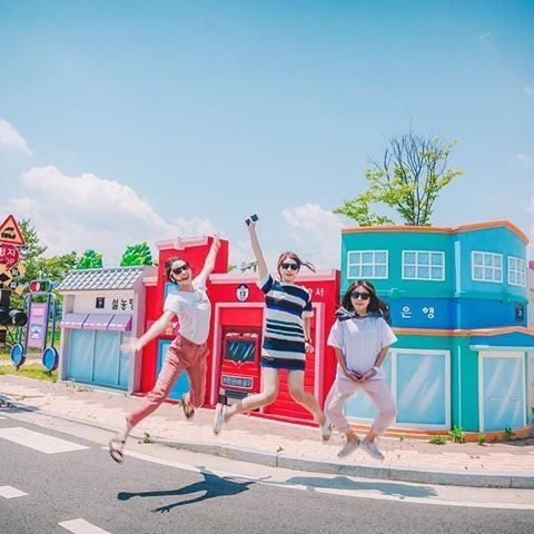 Three women jumping and posing in the vibrant streets of Bicycle Park on a sunny day. / Dispatch