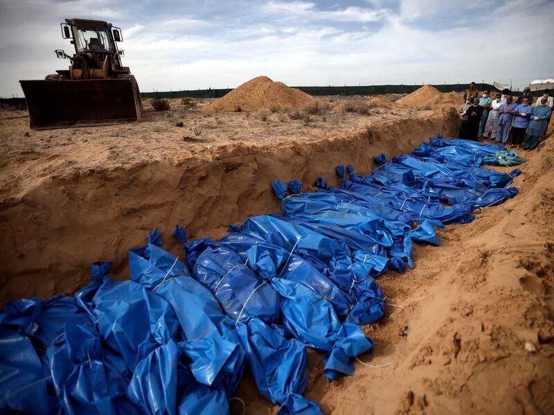 Palestinians pray over bodies of people killed in an Israeli bombardment, brought from the Shifa hospital, before burying them in a mass grave in the town of Khan Younis, southern Gaza Strip, Nov. 22.Mohammed Dahman/AP