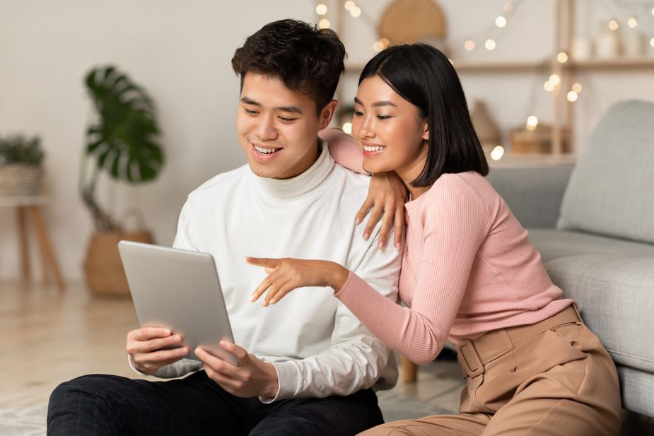 Japanese Boyfriend And Girlfriend Using Digital Tablet Sitting At Home