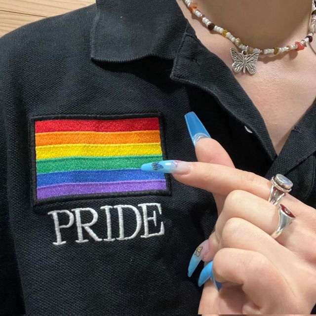 AleXa wearing a Pride Polo shirt while posed with a finger-heart