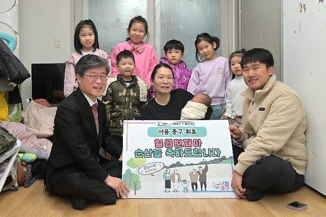 Jung-gu District Mayor Kim Gil-sung (left in the front row) is delivering 10 million won for the fifth child to a couple of the same age, Cho Yong-seok and Jeon Hye-hee (28), who live in Cheonggu-dong, Jung-gu, Seoul on the 21st. Provided by Jung-gu District Office