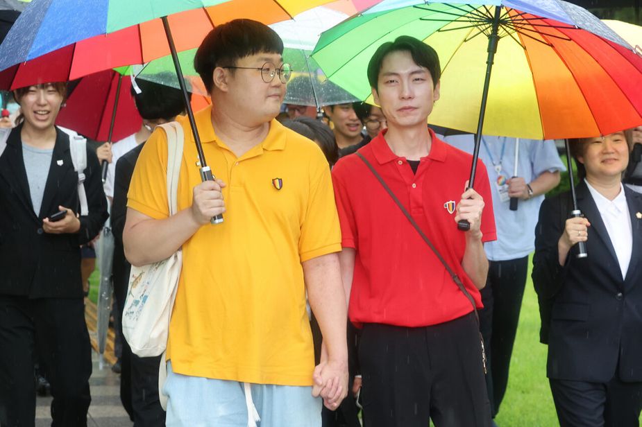So Sung-wook (izquierda) y Kim Yong-min, dos parejas del mismo sexo, se dan la mano al salir de la Corte Suprema en Seocho-gu, al sur de Seúl, el jueves. (Yonhap)